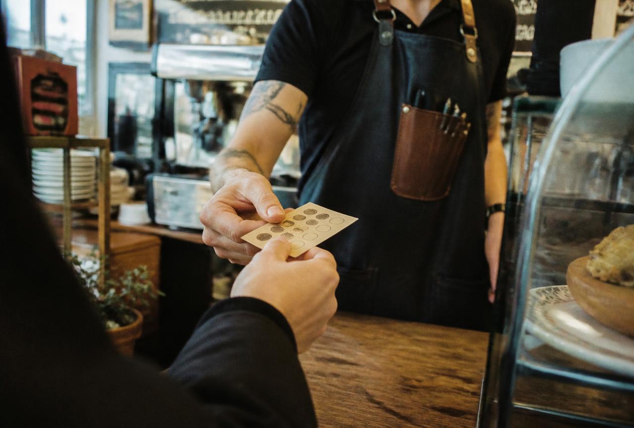 Client tendant sa carte de fidélité au comptoir d’un commerce de proximité