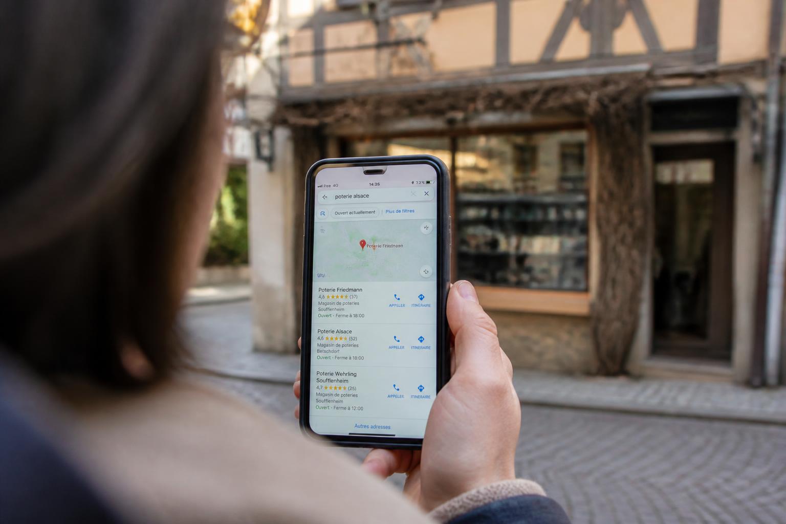 Recherche Google Maps sur un smartphone devant une devanture de commerce à Strasbourg